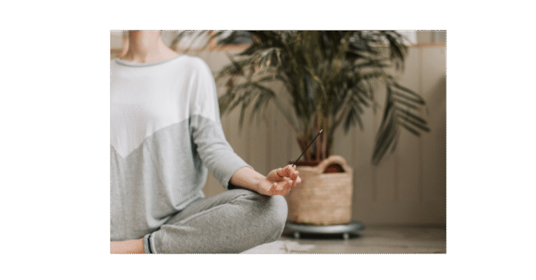 Lady meditating next to plant