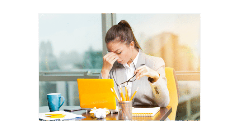 A lady at work with a yellow laptop looking stressed