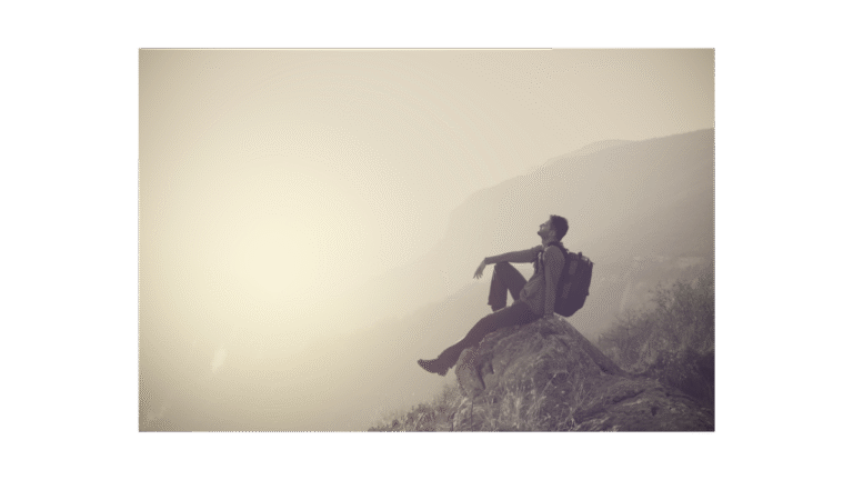 A man on a hillside relaxing from getting to the top