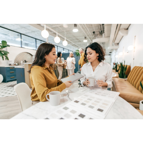 Two business coaches having a drink of coffee in large office